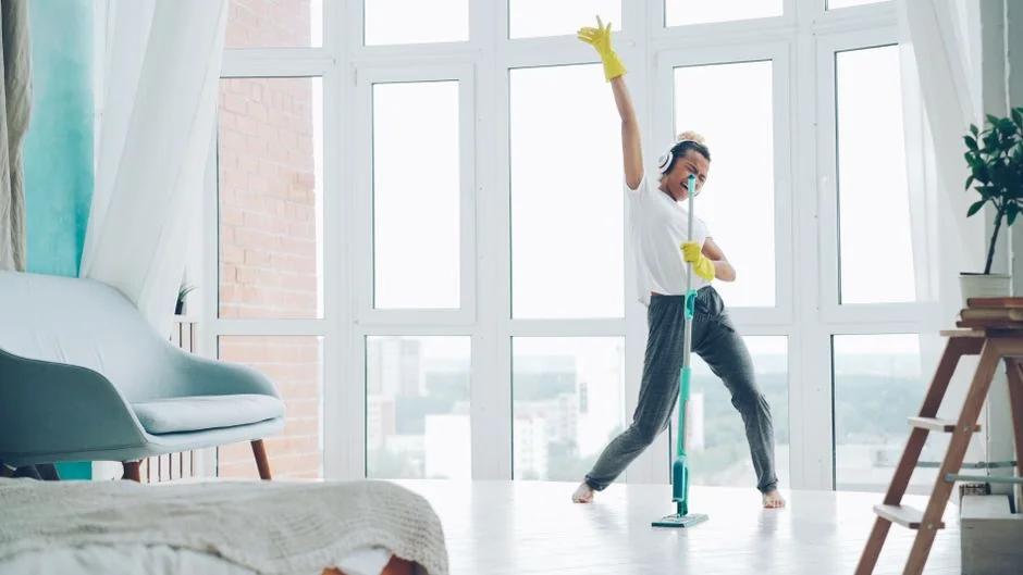 services-03 Deux femmes en tenue de travail nettoient un salon moderne avec un aspirateur et une serpillière.